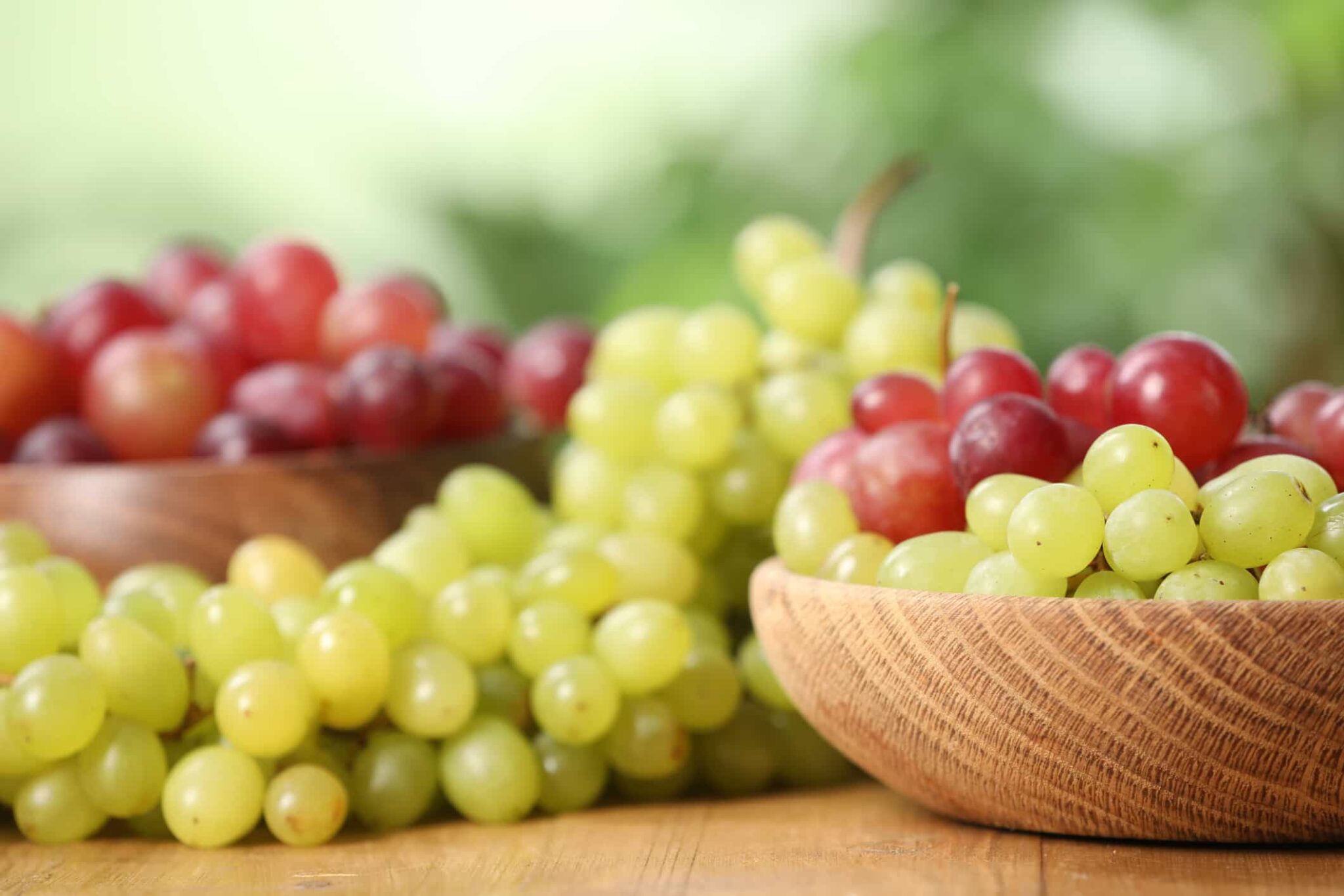 Photo of red and green grapes on a table and in a bowl